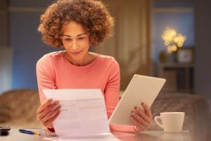 woman with tablet comparing with paper