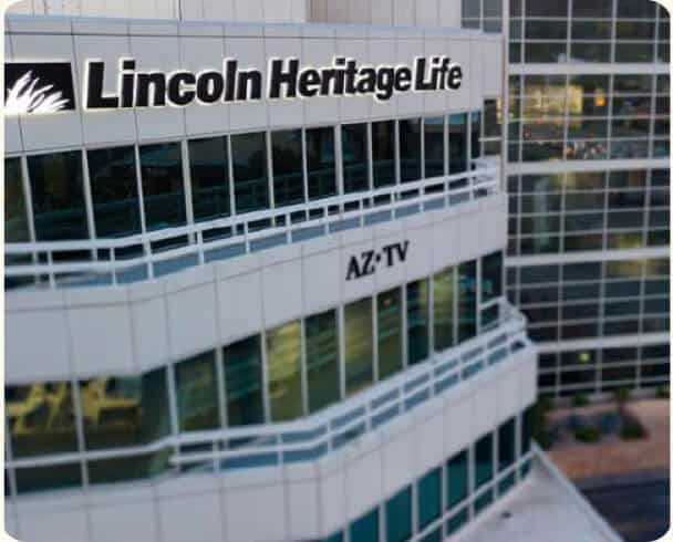 Exterior view of a modern glass office building with signs reading Lincoln Heritage Life and AZ-TV.